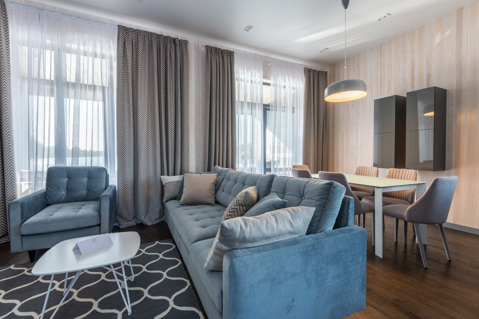 Stylish living room featuring a blue sofa, armchairs, and modern decor within an apartment.